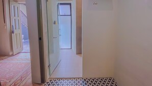 A hallway with a patterned floor, a glass door, and a small shelf on the wall. - Enchanting suite with WiFi, King size-bed in Puebla. excellent location. (Heroica Puebla de Zaragoza)