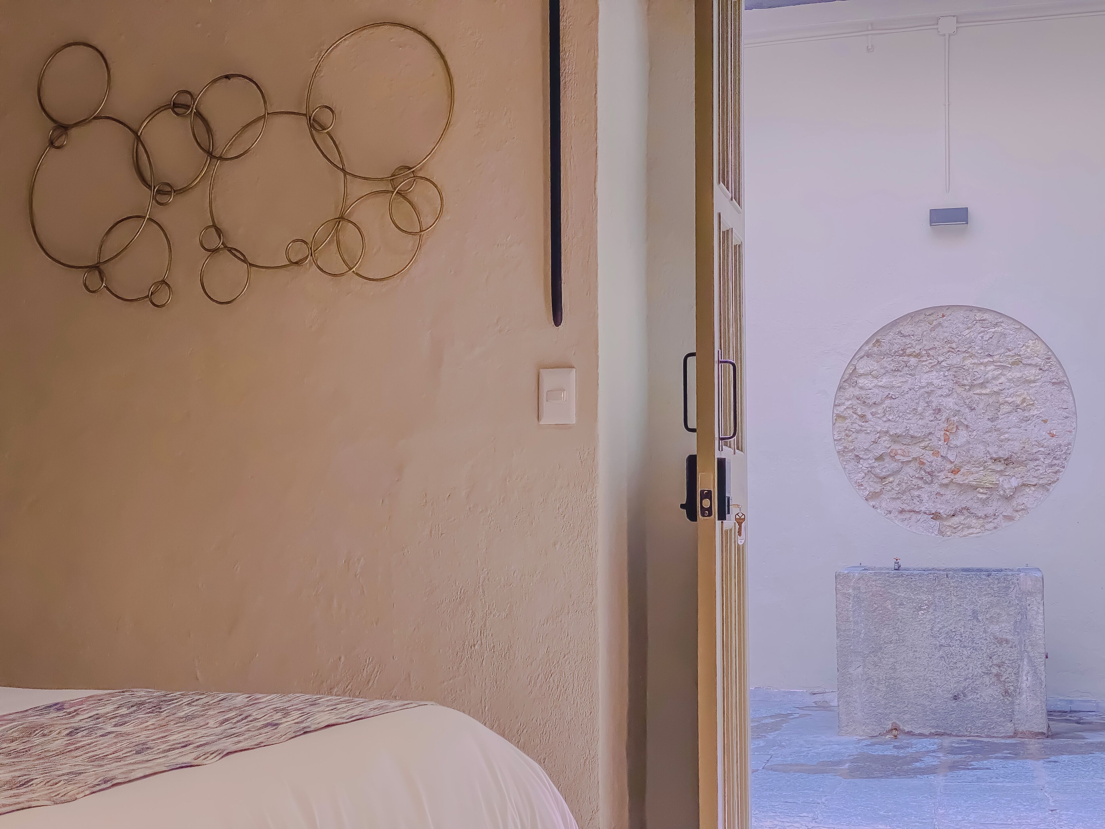 Ein Zimmer mit einem Bett, einem runden Wandbild und einer Tür zu einem anderen Raum.