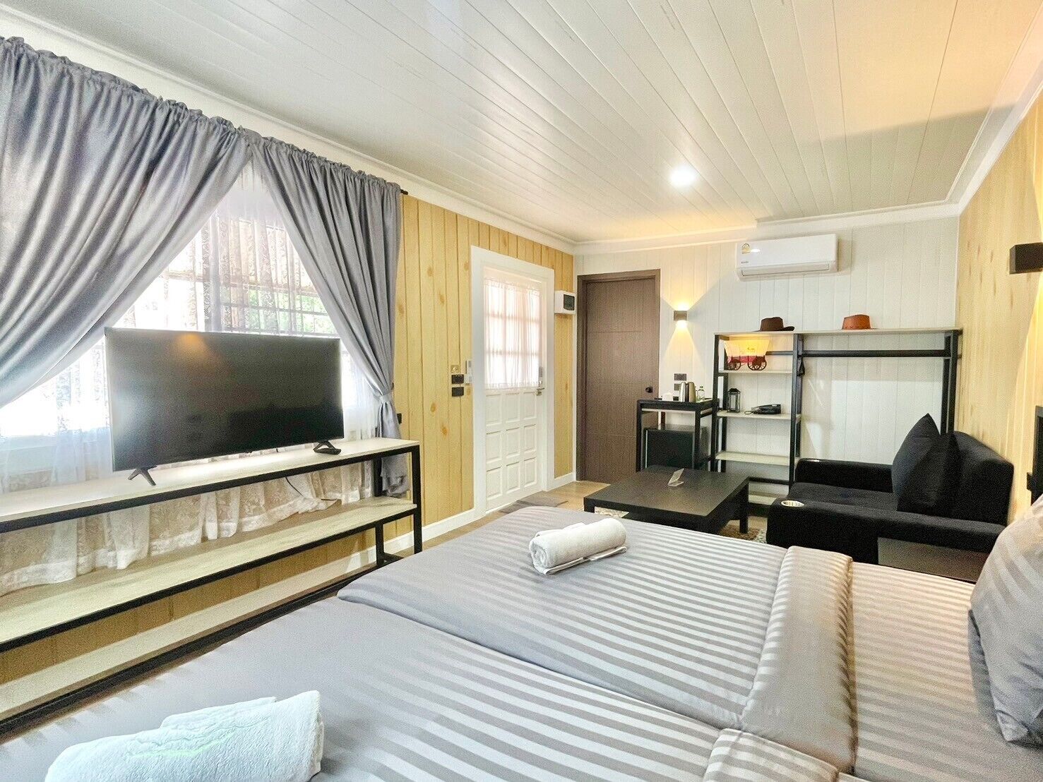 A hotel room with two beds, a TV, a desk, and a chair.