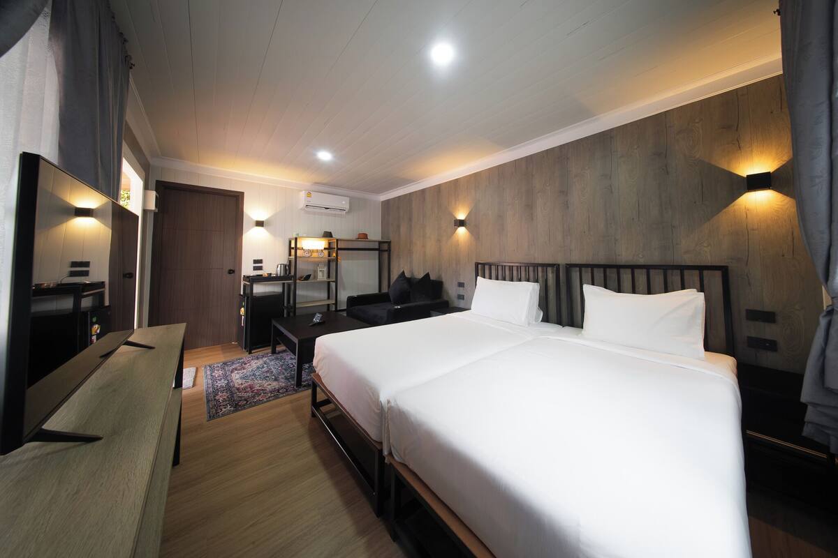 A hotel room with a large bed, a desk, a chair, a mirror, and a wall-mounted light fixture.
