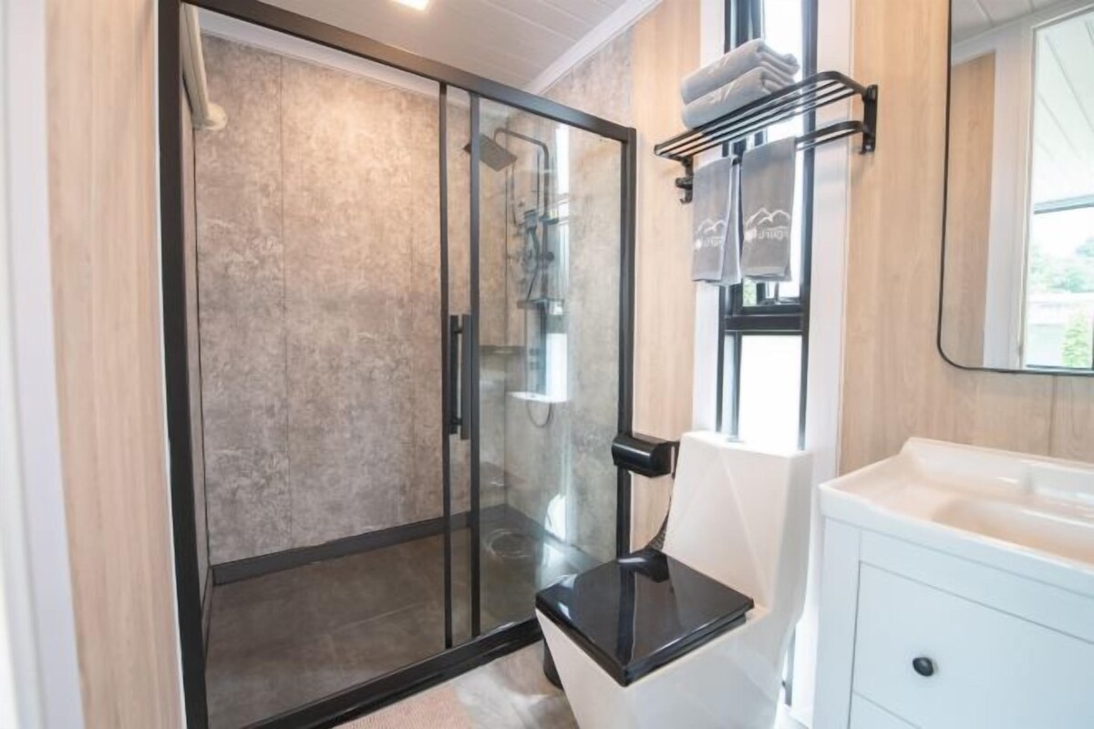 A modern bathroom with a glass-enclosed shower, a white sink, and a towel rack.