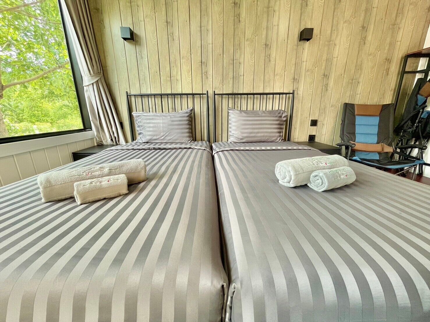 Una cama doble con ropa de cama a rayas, dos almohadas y toallas enrolladas.