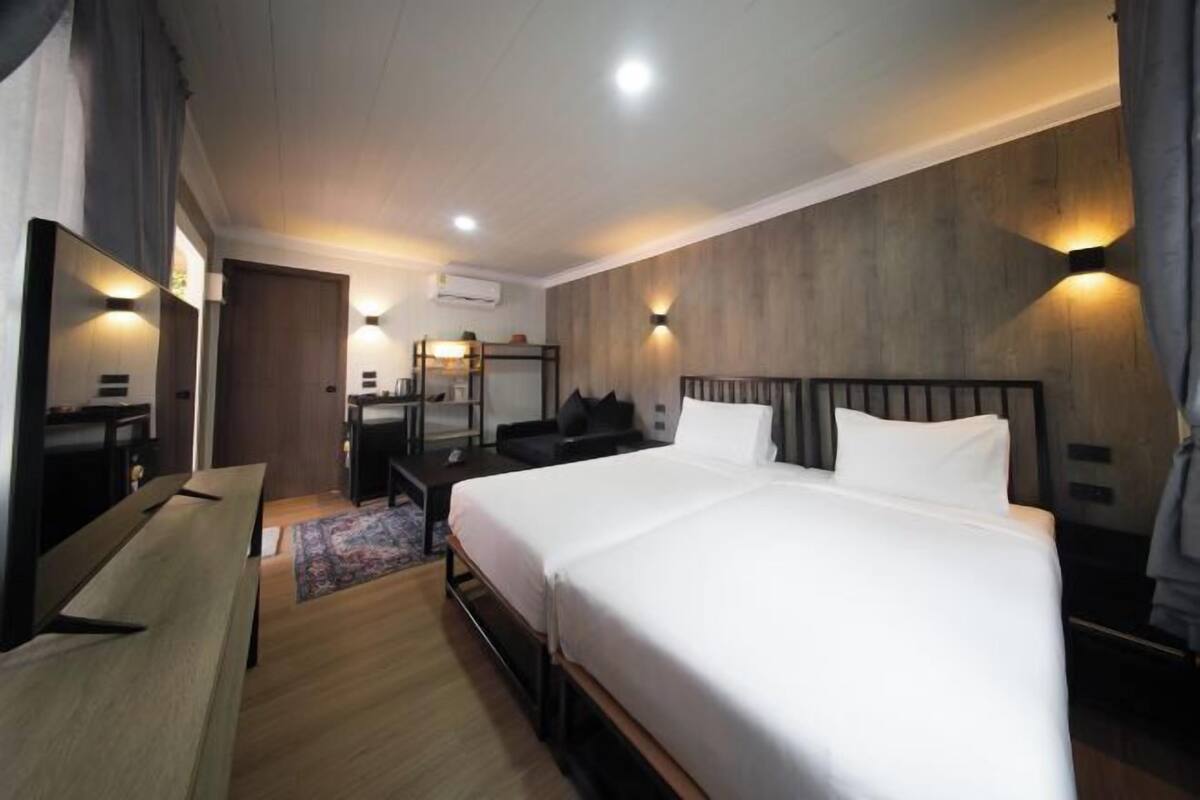 A hotel room with a large bed, a desk, a chair, and a mirror.