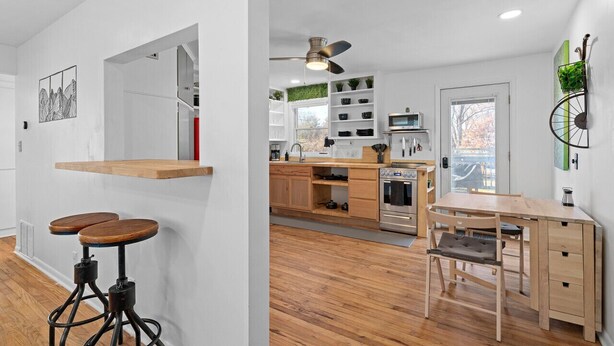 A modern kitchen with wooden cabinets, a dining table, and bar stools. - Overland Park Retreat (Overland Park)