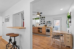 A modern kitchen with wooden cabinets, a dining table, and bar stools. - Overland Park Retreat (Overland Park)
