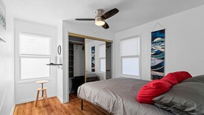 A bedroom with a bed, a ceiling fan, a wardrobe, and a painting on the wall. - Overland Park Retreat (Overland Park)