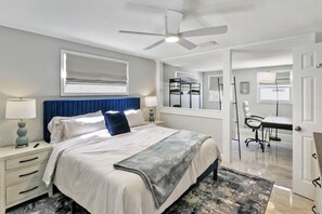 A bedroom with a bed, bedside tables, a desk, and a chair.