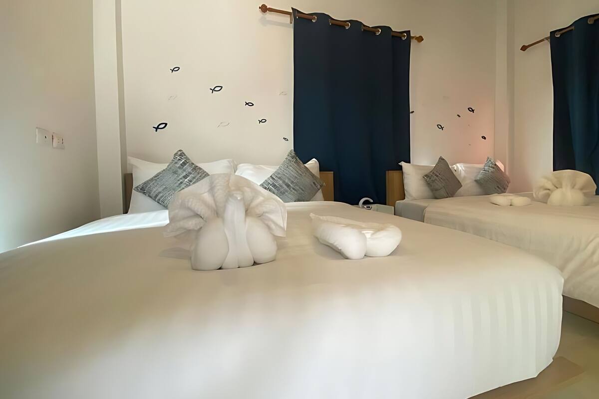 A hotel room with two beds, each with white bedding and decorative pillows.