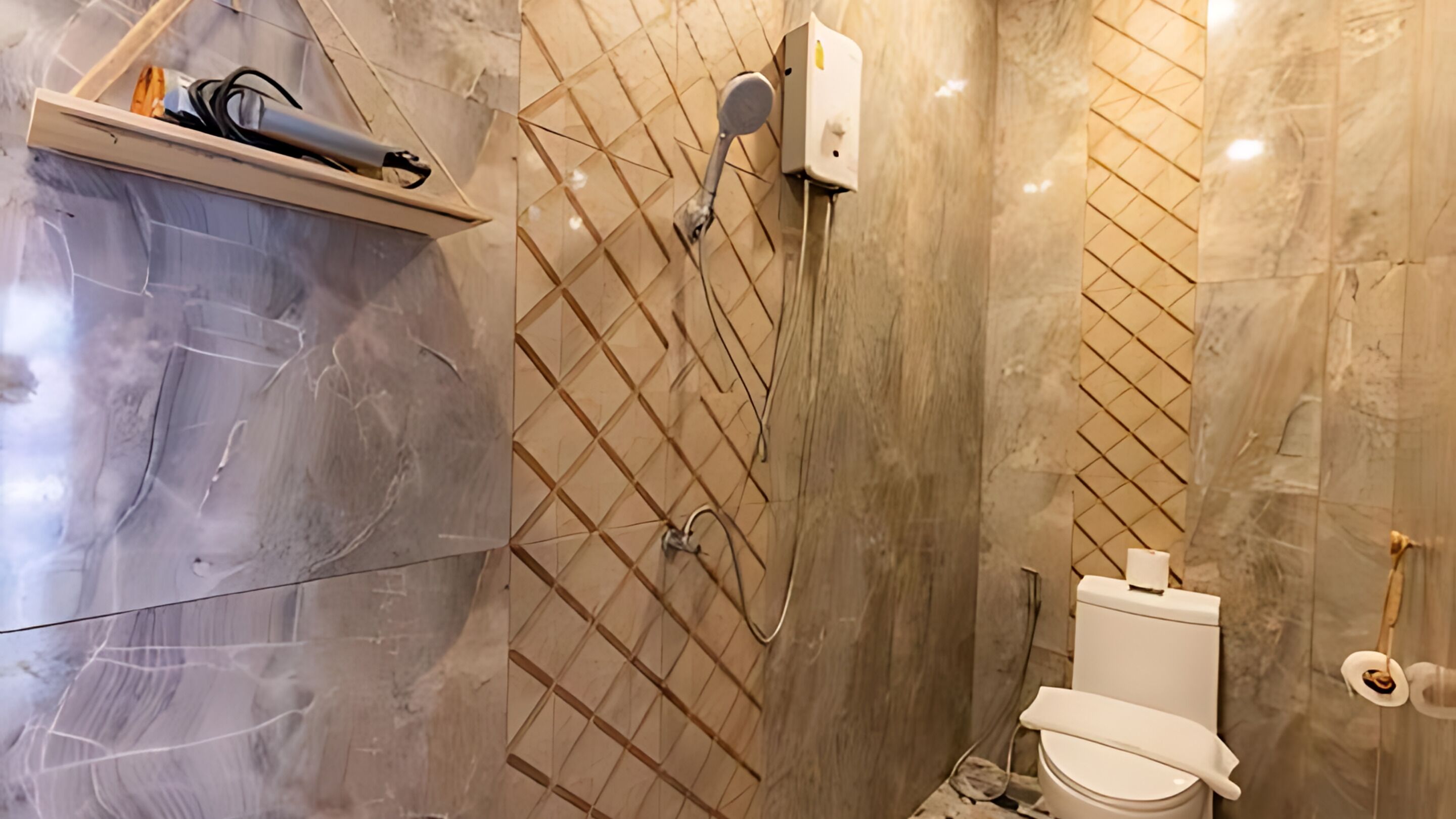 Une salle de bain avec un sol en marbre, une douche équipée d’un pommeau de douche amovible, des toilettes et une étagère contenant des articles de toilette.