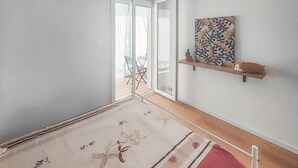 A hallway with a patterned rug, a wooden floor, a glass door leading outside, and a shelf with decorative items. - 1 bedroom nice apartment in Palavas-Les-Flots (Palavas-Les-Flots)