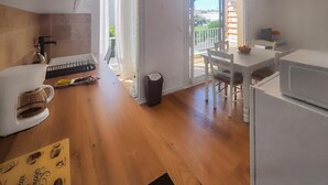 A compact kitchen with a coffee maker, a trash bin, and a dining table with chairs. - 1 bedroom nice apartment in Palavas-Les-Flots (Palavas-Les-Flots)