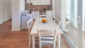 A modern kitchen with white cabinets, a microwave, and a coffee maker. There is a dining table with chairs and a basket of fruit. - 1 bedroom nice apartment in Palavas-Les-Flots (Palavas-Les-Flots)