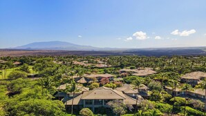 A residential area with houses featuring tiled roofs and surrounded by lush greenery.