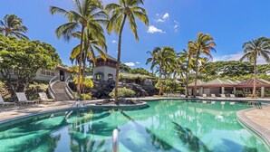 A swimming pool with lounge chairs and palm trees.