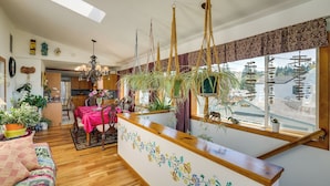 A spacious living area with a wooden reception desk, a dining table with chairs, and a kitchen in the background. - Sunset + Ocean Views: Serene Camano Escape (Camano)