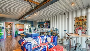 A modern living room with a sofa, a dining table, and a kitchen area. - Fallbrook Airplane Home w/ Fire Pit & Mtn Views! (Fallbrook)