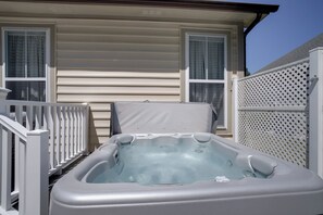 A hot tub in front of a house with a white fence and two windows. - Deck, Hot Tub & Resort Amenities: Ocean View Gem (Ocean View)