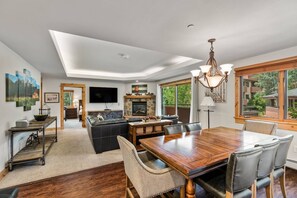 A spacious living area with a dining table, comfortable seating, a fireplace, and a television.