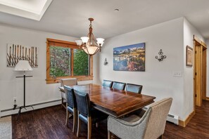 A dining room with a wooden table, leather chairs, a chandelier, and artwork on the walls.