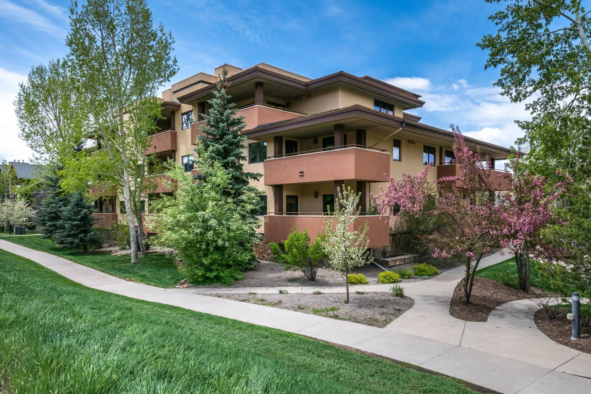 A multi-story building with a flat roof, surrounded by well-maintained lawns and trees.