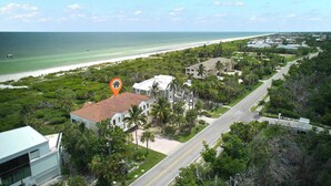 A coastal area with a beach, a road, and a building with a red roof. - St. Croix Four | Gorgeous Beachfront Townhome | Sun, Sand & Sea (Sanibel)