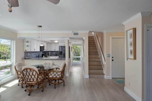 Une cuisine spacieuse équipée d’appareils modernes, un coin repas avec des chaises en osier et un escalier menant à un autre niveau.