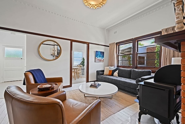 A spacious living room with a leather sofa, a round coffee table, and a fireplace.