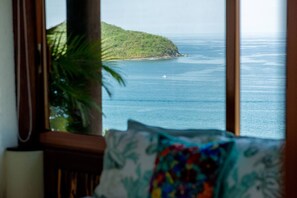 A view through a window of a coastal landscape with a small island and calm sea.