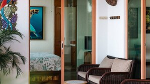 A room with a bed, a wicker sofa, a small table, and a glass door leading to a balcony. - Best Views of Zihua 3Bed 3 Bath luxury (Zihuatanejo)