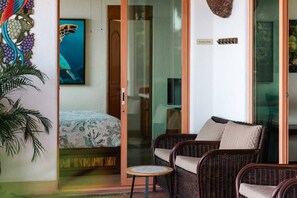 A room with a bed, a wicker sofa, a small table, and a glass door leading to a balcony. - Best Views of Zihua 3Bed 3 Bath luxury (Zihuatanejo)