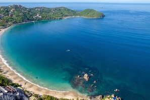 A coastal landscape with a beach, clear water, and a small island. - Best Views of Zihua 3Bed 3 Bath luxury (Zihuatanejo)