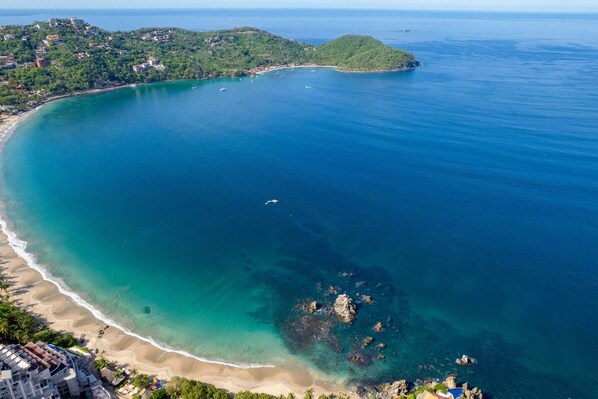 A coastal landscape with a beach, clear water, and a small island.