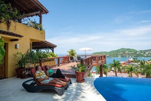 A poolside area with a view of the sea, a wooden deck, and potted plants. - Best Views of Zihua 3Bed 3 Bath luxury (Zihuatanejo)