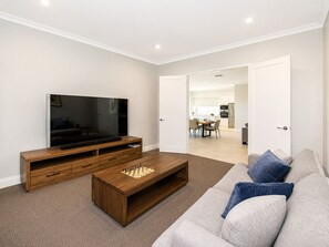 A living room with a TV, wooden entertainment unit, and a chessboard. - A Waterside Paradise (Geographe)