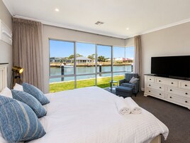 Habitación de hotel con una cama grande, televisor, escritorio y vista a un cuerpo de agua.