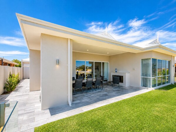 A modern house with a covered patio, a fireplace, and a large sliding glass door. - A Waterside Paradise (Geographe)