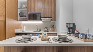 A modern kitchen with wooden cabinets, a microwave, a kettle, and a coffee maker. - Zantamar 307B: Beachfront Suites w Ocean Views (Cruz de Huanacaxtle)