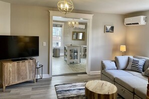 A living room with a television, a sofa, a lamp, and a wooden coffee table. - Historic dog-friendly home 2 blocks to Main St (Annapolis)