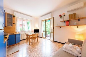 A compact hotel room with a kitchenette, dining area, and a sofa with towels.