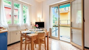 A dining area with a table, chairs, a TV, and a view of a balcony. - Beautiful Flat in Rapallo (Rapallo)