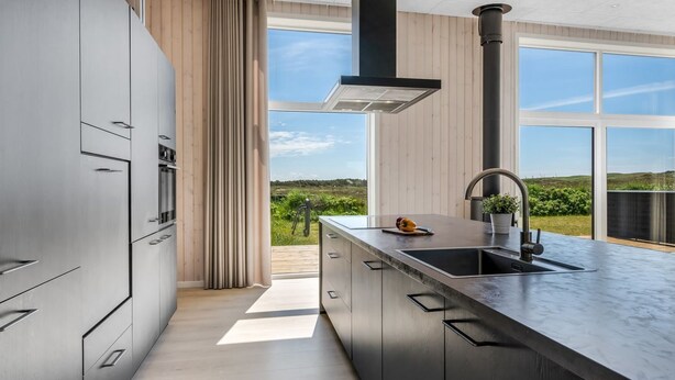 Una cucina moderna con una grande isola, forno integrato e vista sull'esterno.