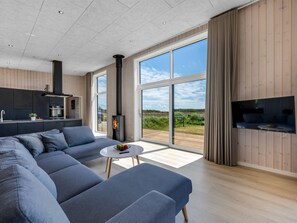 A modern living room with a sofa, a small table, a TV, and a large window offering a view of the outdoors.