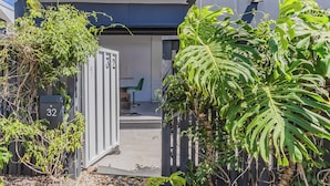 A residential building with a gated entrance, a mailbox, and a chair outside.
