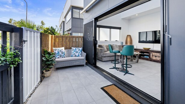 A modern outdoor living area with a sofa, chairs, and a dining table.