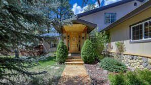 A house with a stone pathway leading to a wooden front door, surrounded by well-maintained landscaping and trees.