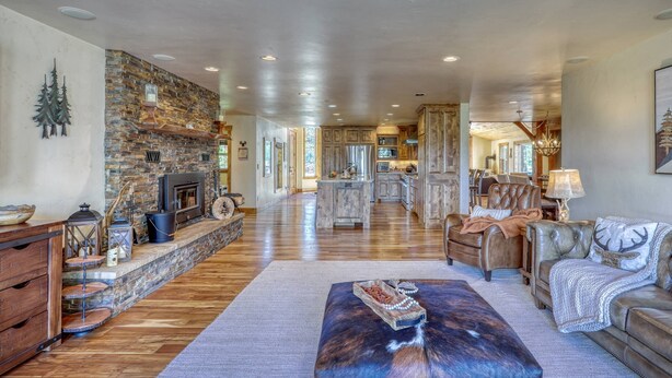 A spacious living area with a stone fireplace, leather furniture, and a kitchen in the background.