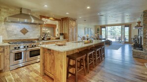 A spacious kitchen with a large island, wooden cabinets, and a stone fireplace.