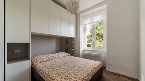 A bedroom with a bed, built-in storage, a window, and a ceiling light fixture. - GuestHost - Monteverde Classy Apartment (Roma)