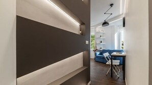 A modern interior with a dark wall, a wooden floor, a blue sofa, and a table with chairs. - GuestHost - Monteverde Classy Apartment (Roma)