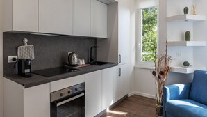 A modern kitchen with white cabinets, a black countertop, and a built-in oven. There is a window with a view of greenery outside. - GuestHost - Monteverde Classy Apartment (Roma)